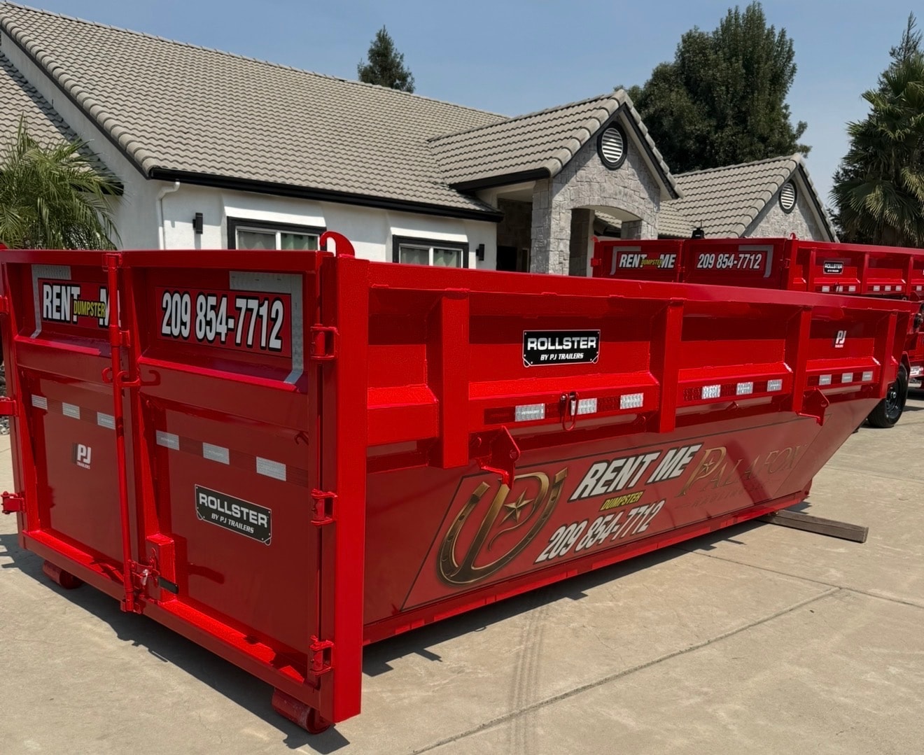 Palafox Hauling LLC red roll-off dumpster trailer at a residential property